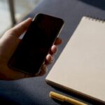 Hand holding smartphone over golden desk