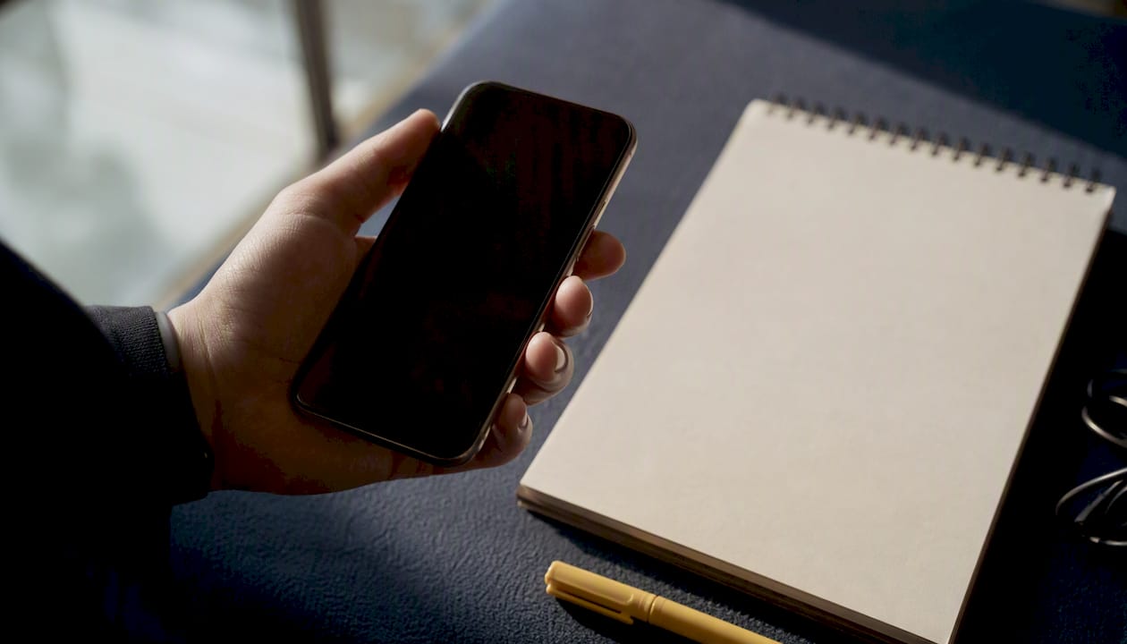 Hand holding smartphone over golden desk