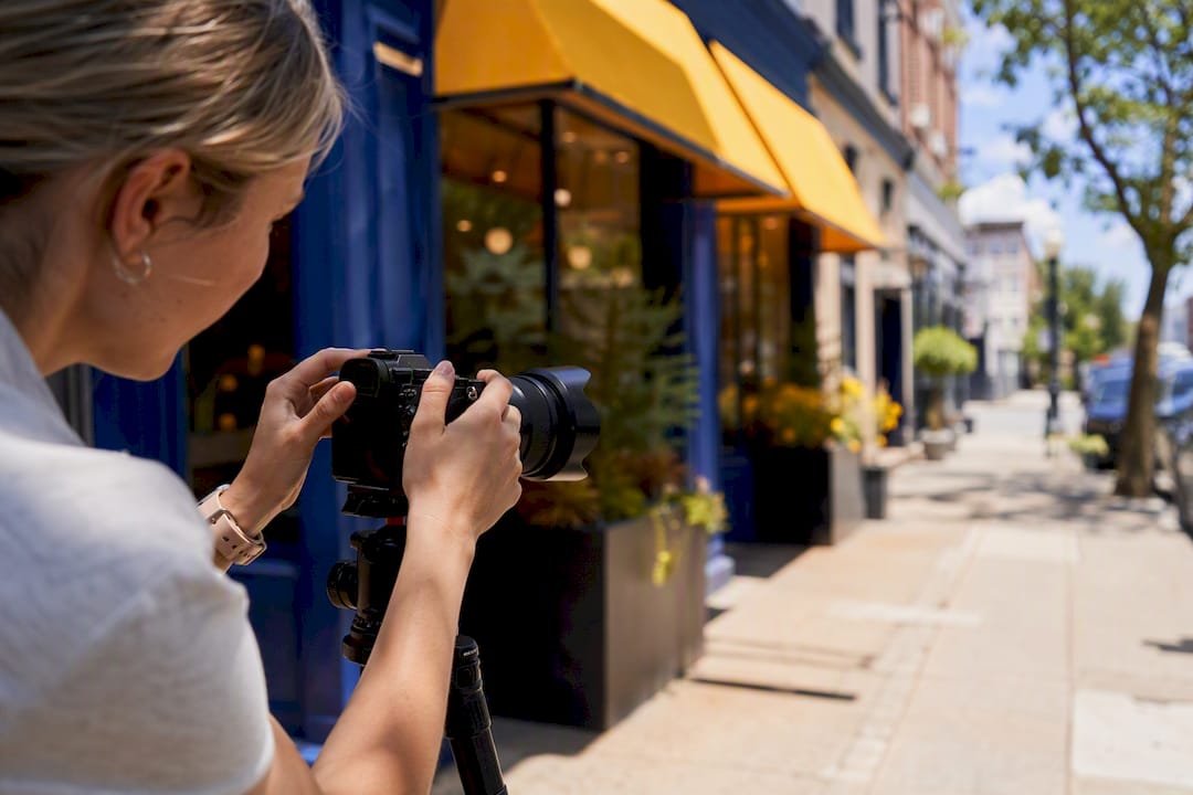 Envision Marketing Agency | Multi Location SEO: A Systems Playbook for Scaling Photographer adjusting lens at business storefront