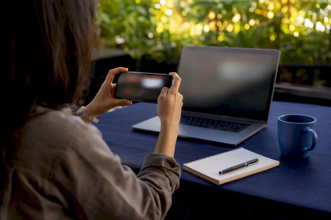 Envision Marketing Agency | Landing Page vs Homepage: When to Use Each for Conversions Hands capturing dashboard screenshot with phone