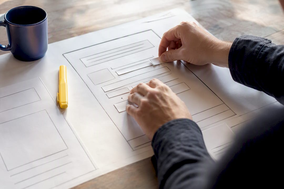 Envision Marketing Agency | Marketers: Prioritize Low Effort Fixes to Boost Contact Form Conversion Hands adjusting website form wireframe board